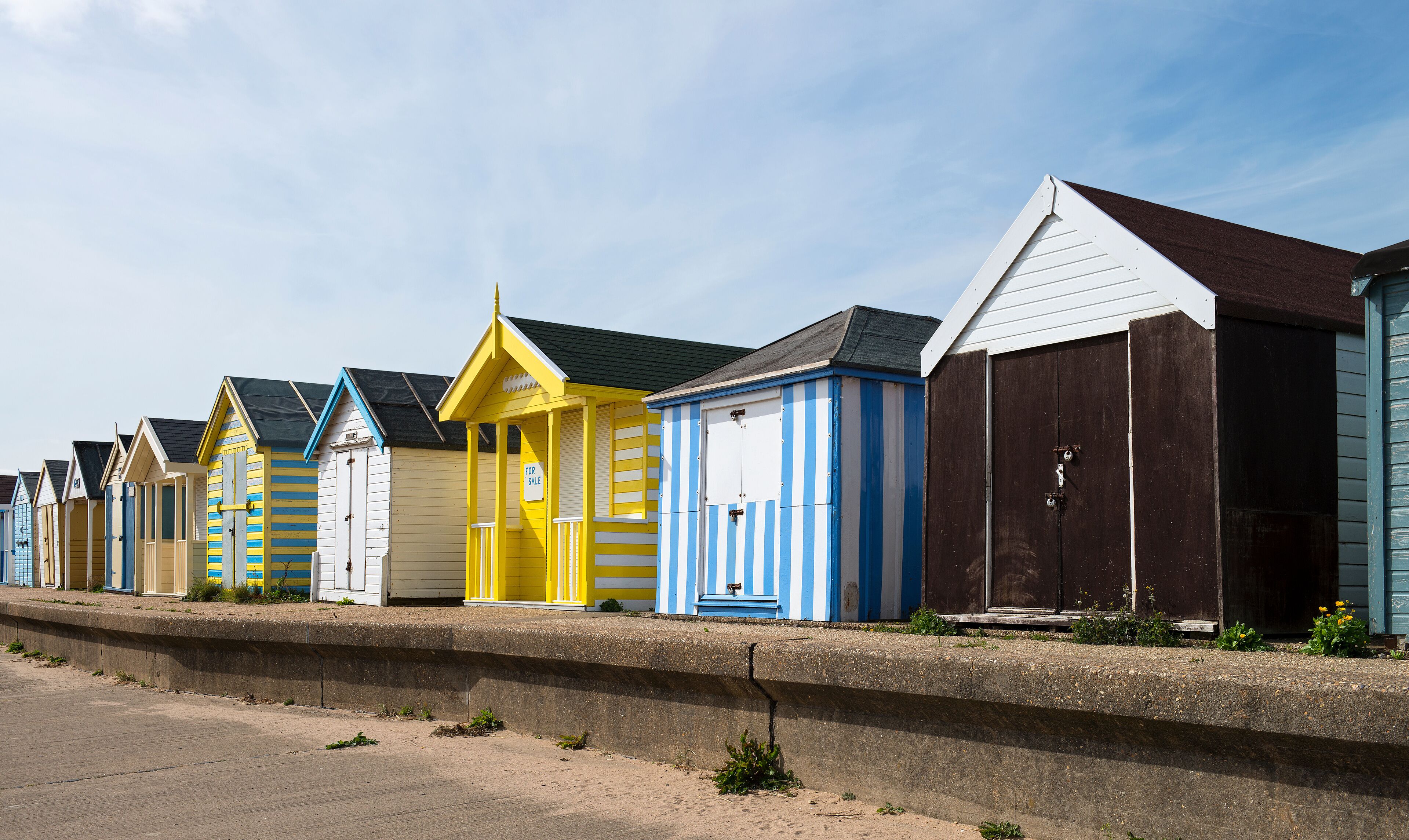 A row of colorful beach huts along a seaside promenade.
