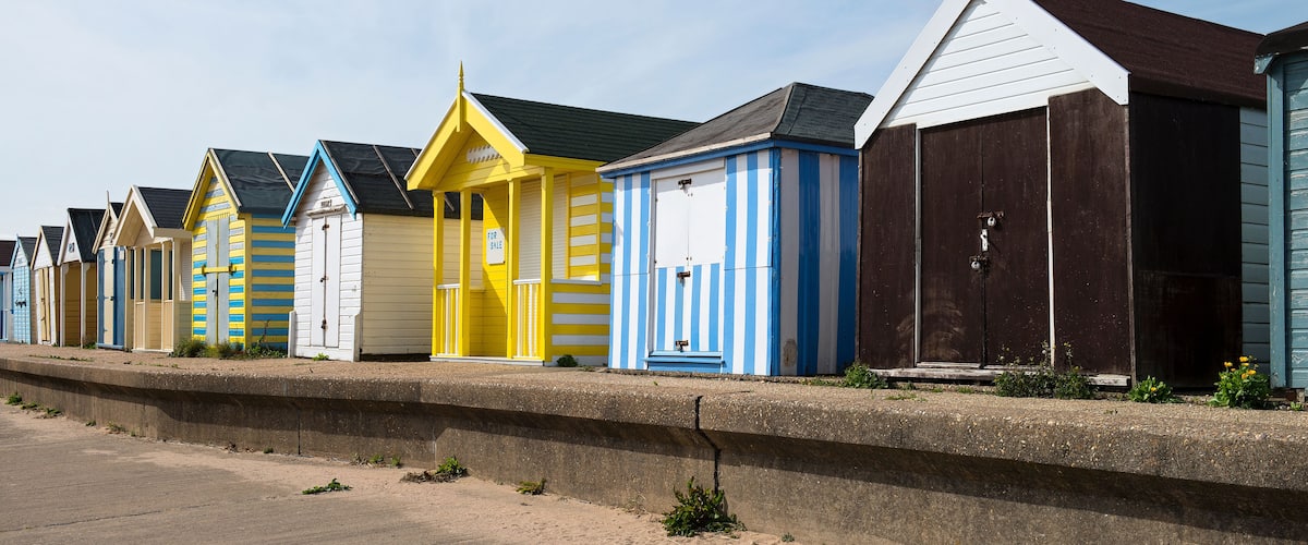 A row of colorful beach huts along a seaside promenade.