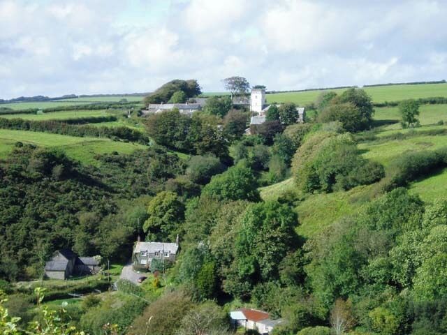 A rural landscape with rolling hills, scattered houses, and a prominent white tower.