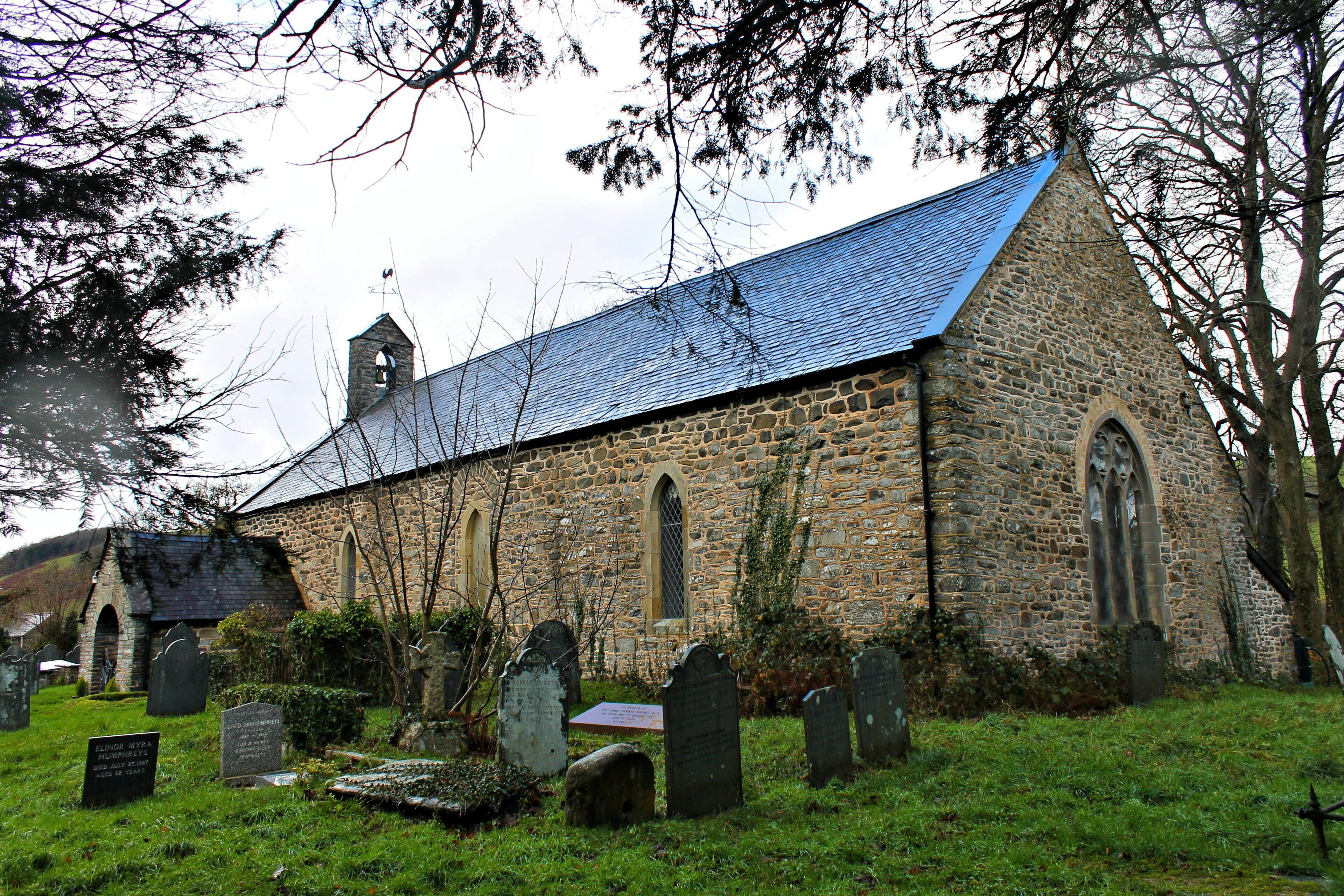 A stone church with a steeply pitched roof and a bell tower.