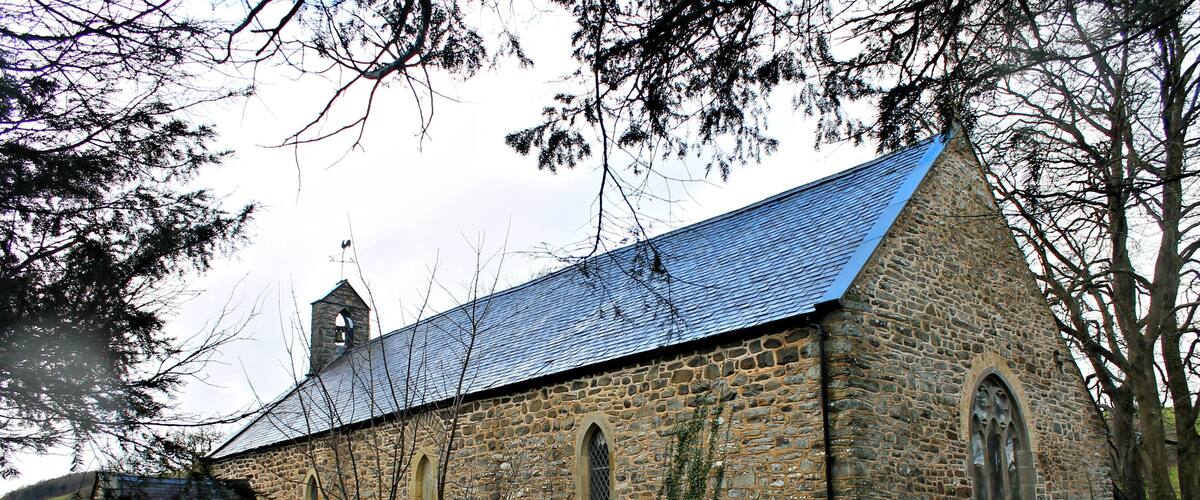 A stone church with a steeply pitched roof and a bell tower.