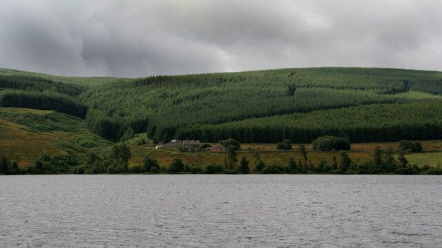 A lake with a forested hillside in the background.