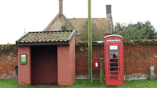 Bus shelter, postbox and telephone box. On the village green. The roof and chimneys seen in the background belong to the farmhouse of > 702079. Caston is located near the British Army's battle training area and surrounded by farmland on all sides. It is believed that the village dates back as far as to the 8th or 9th century. Caston has a large village green that is surrounded by picturesque cottages; in 1988 the village won the Best Kept Village Competition for villages under a population size of 500.