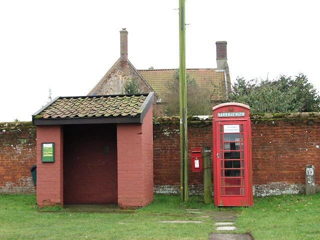 A red telephone booth and a small brick building with a tiled roof.