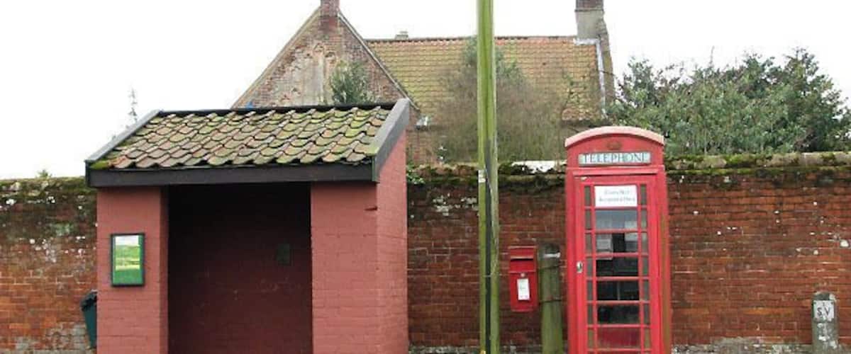 A red telephone booth and a small brick building with a tiled roof.
