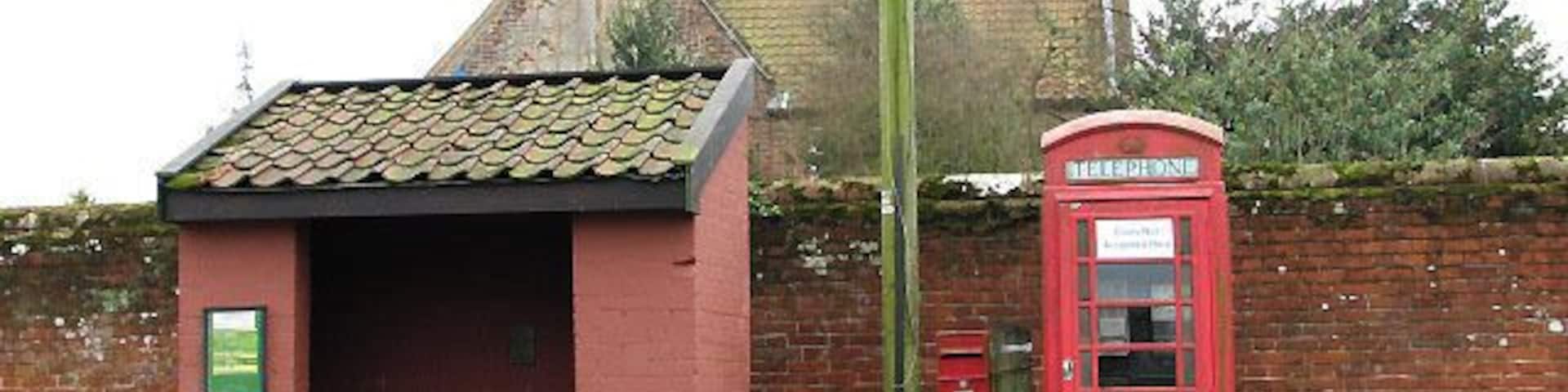 A red telephone booth and a small brick building with a tiled roof.