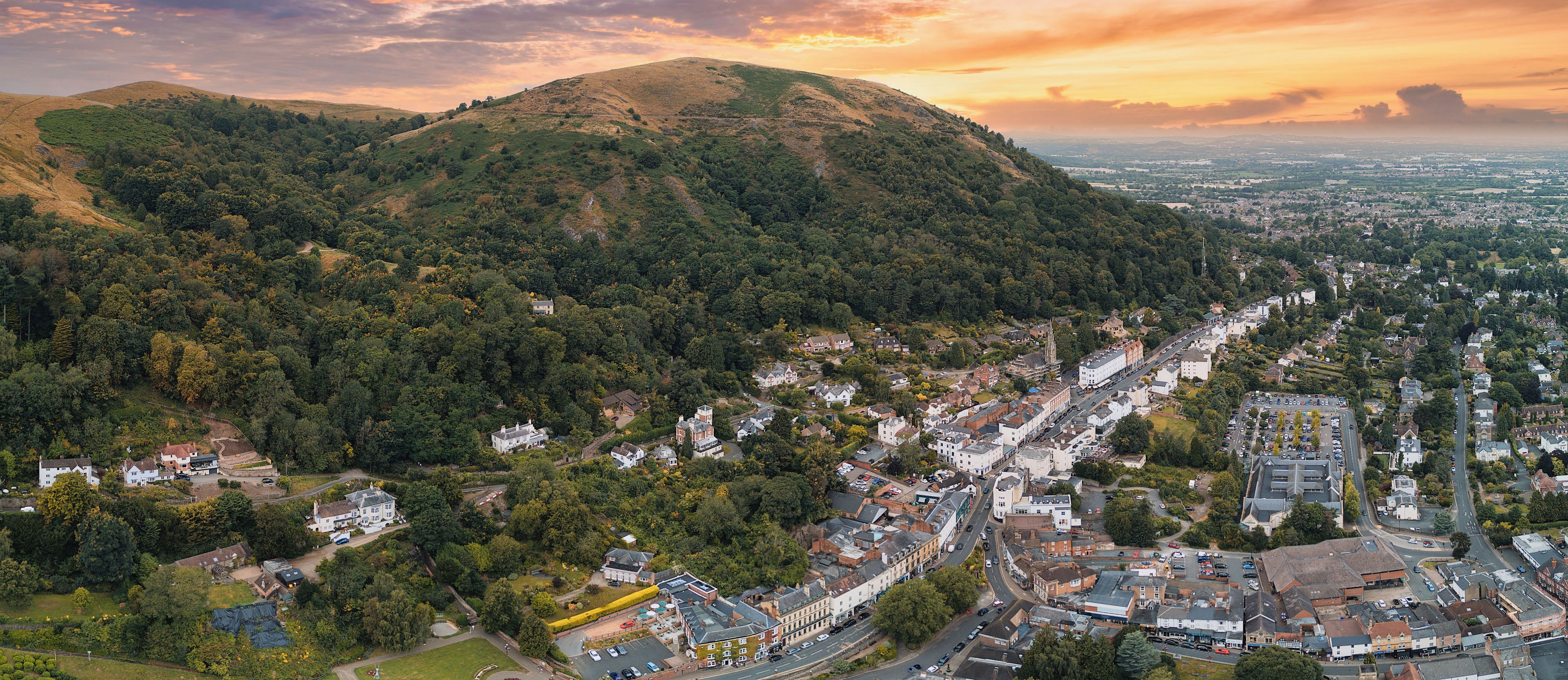 A town nestled in a valley with a prominent hill in the background.
