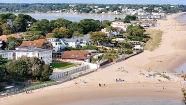 Uma vila costeira com uma praia de areia, casas e um rio.