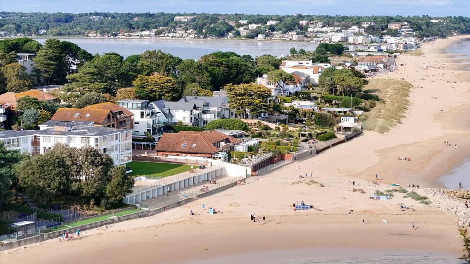 A coastal town with a sandy beach, houses, and a river.