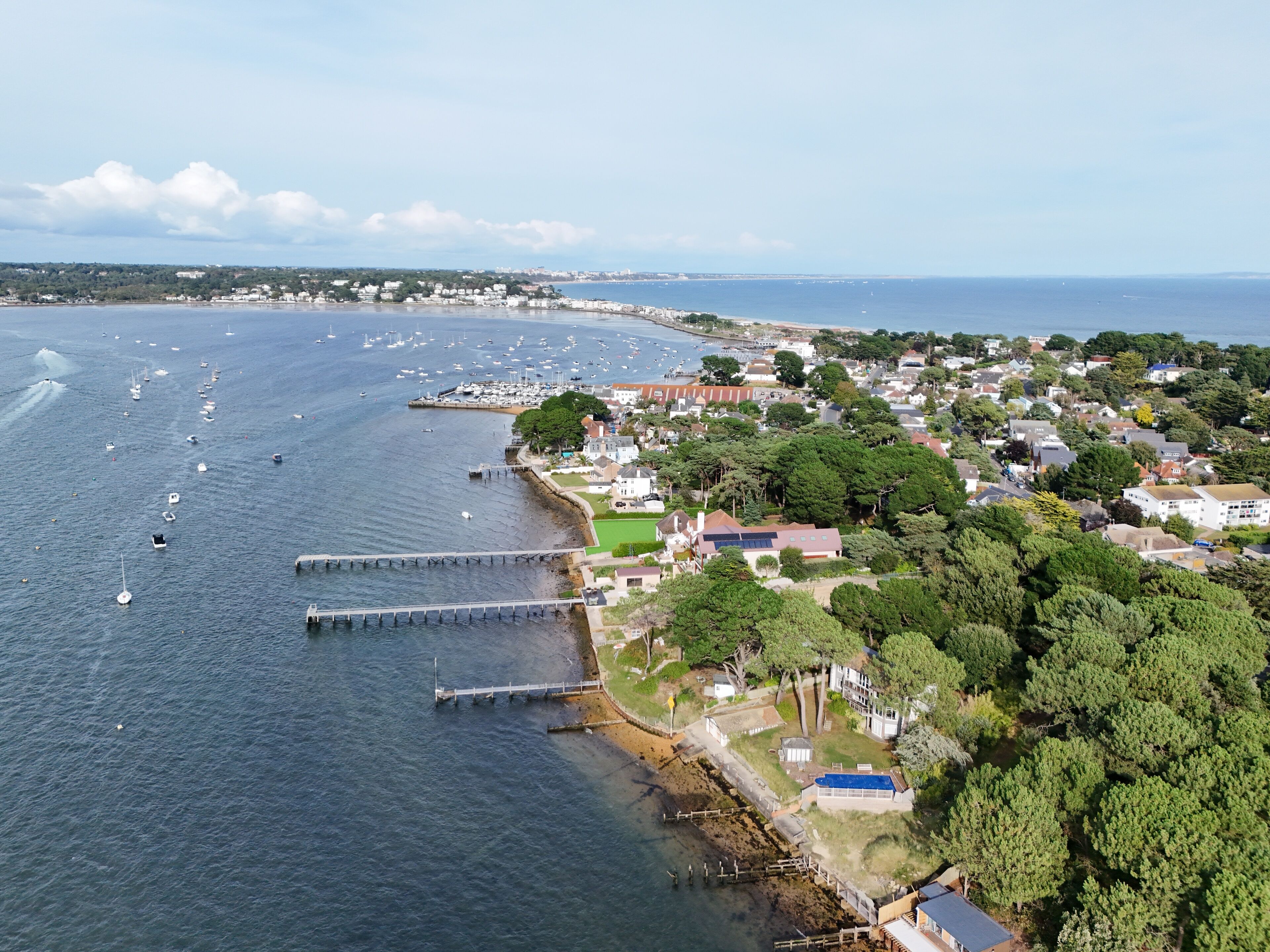 An aerial view of a coastal town with a marina, houses, and a pier.