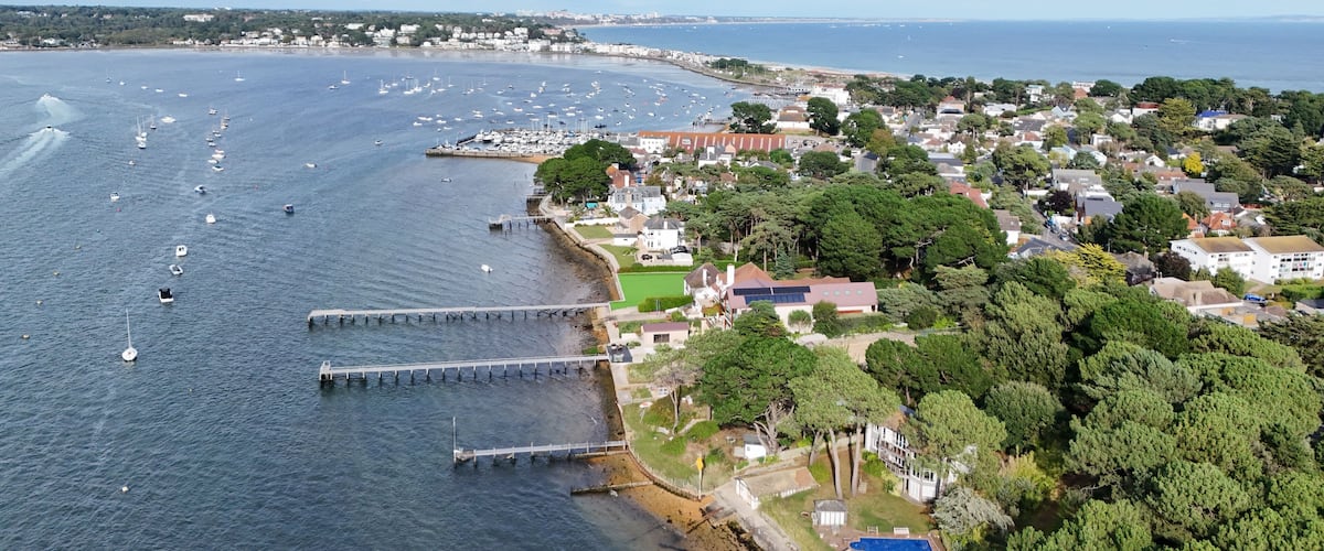 An aerial view of a coastal town with a marina, houses, and a pier.