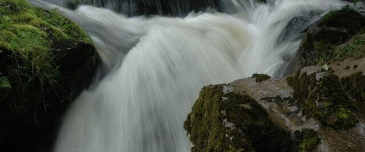 A waterfall cascading over moss-covered rocks.