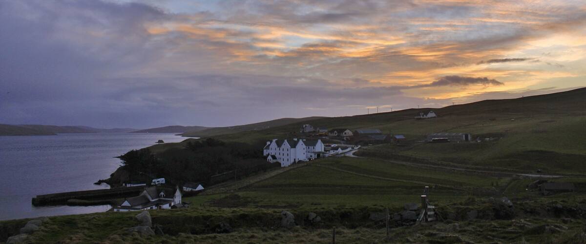 A coastal landscape with rolling hills, a body of water, and white houses.