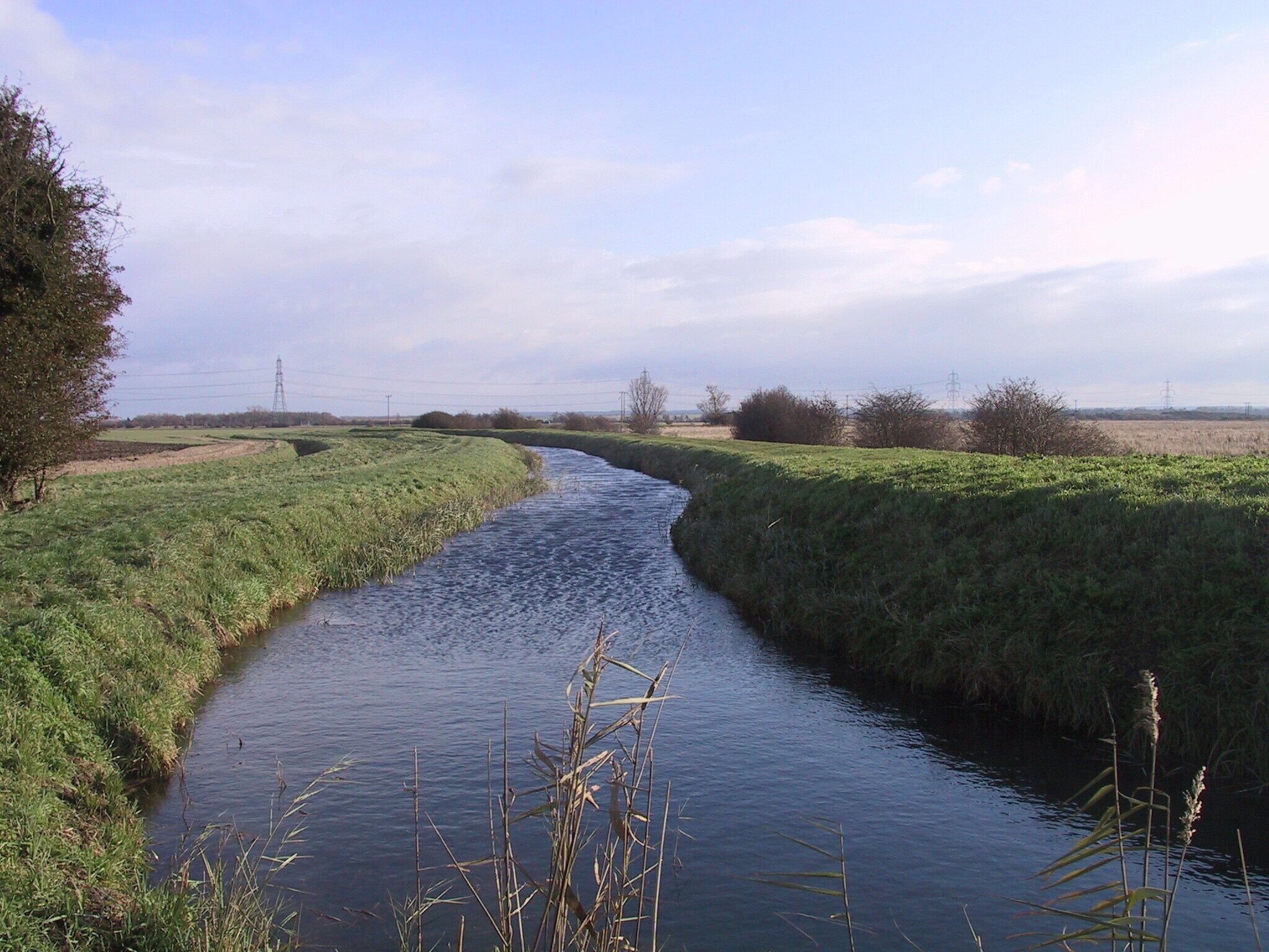 New River New River flows from Exning, through Landwade, Burwell, Fordham and Wicken, where it becomes Monk's Lode, which joins to Wicken Lode. This photograph was taken from the Wicken footbridge, close to where it becomes Monk's Lode. This is the fen-edge, on the right is Guinea Hall Fen (part of the Wicken Fen National Trust National Nature Reserve) and to the left is Wicken village, which is slightly uphill.