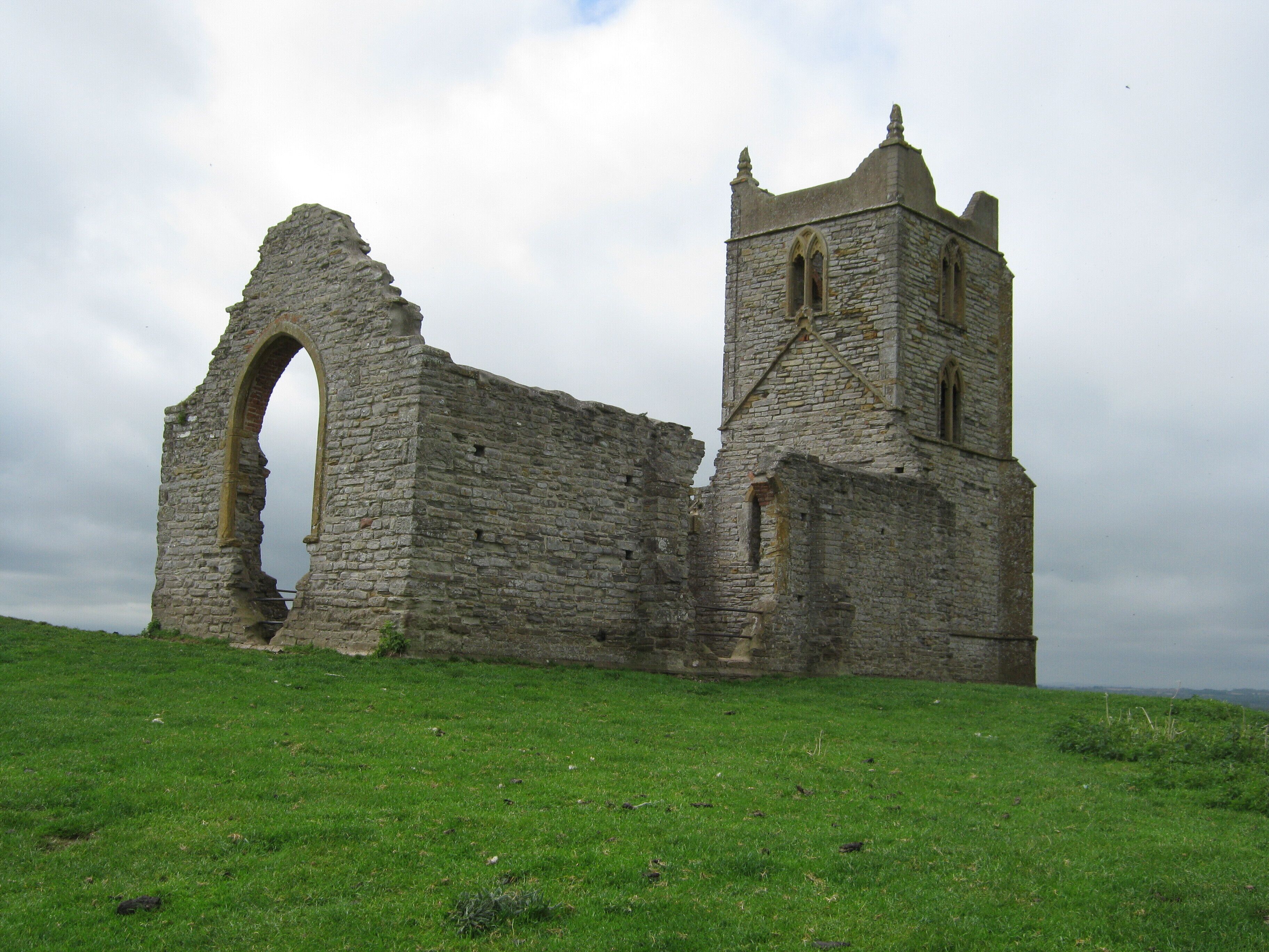 A stone ruin with a large archway and a tower.