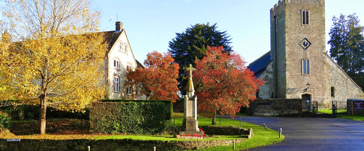 A historic stone tower, a church, and a residential building with autumn foliage.