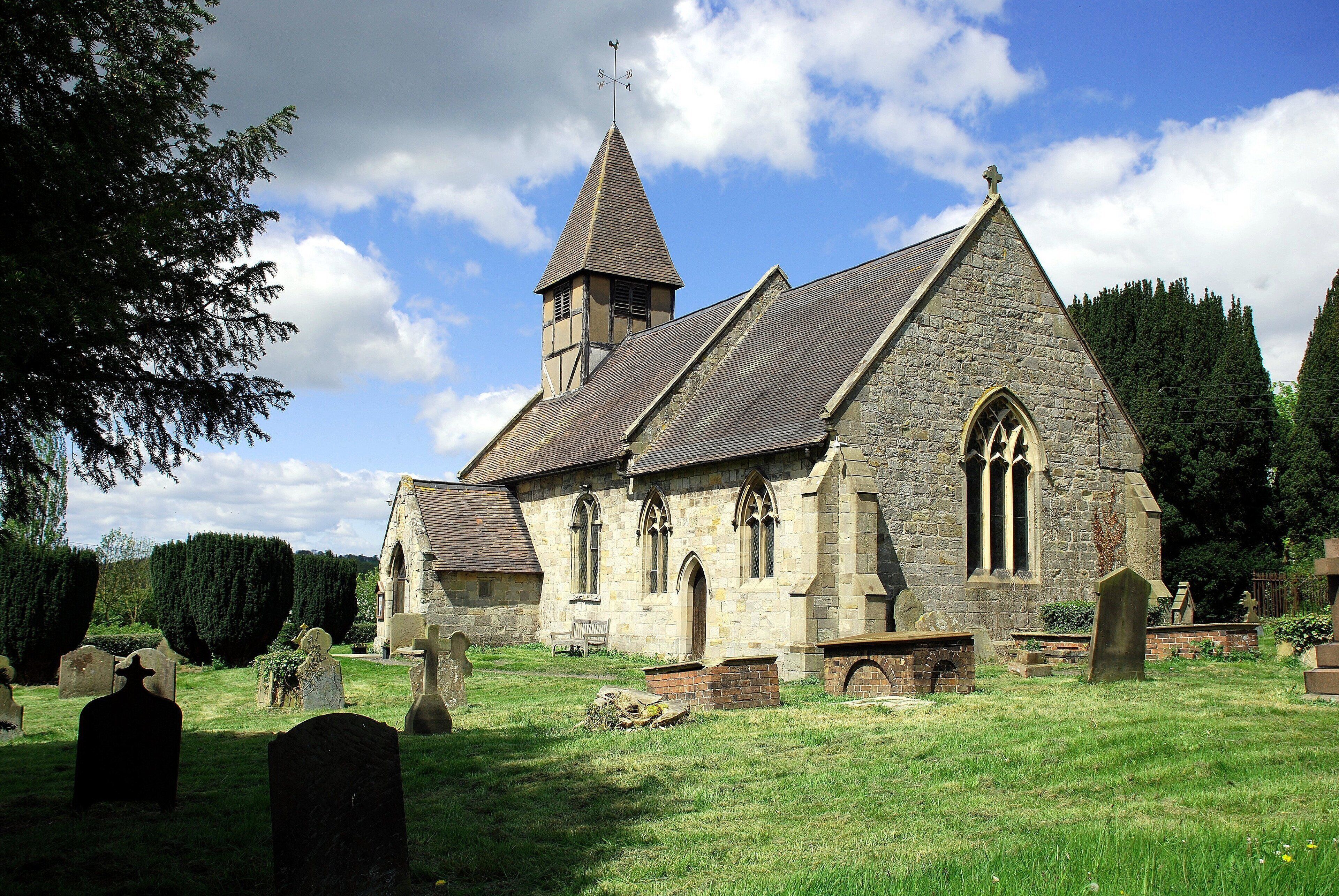 A historic church with a prominent steeple and a graveyard in front.