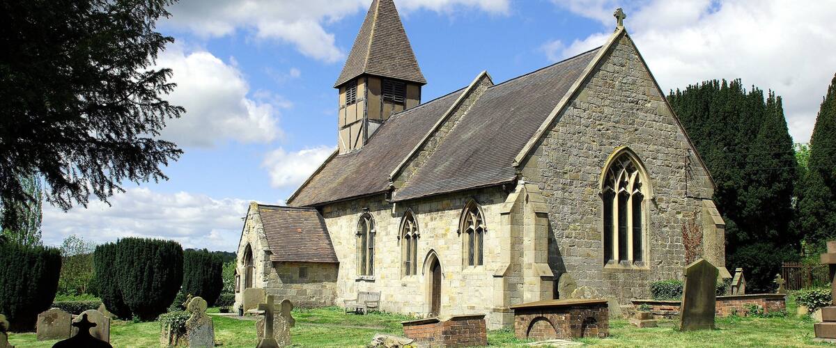A historic church with a prominent steeple and a graveyard in front.