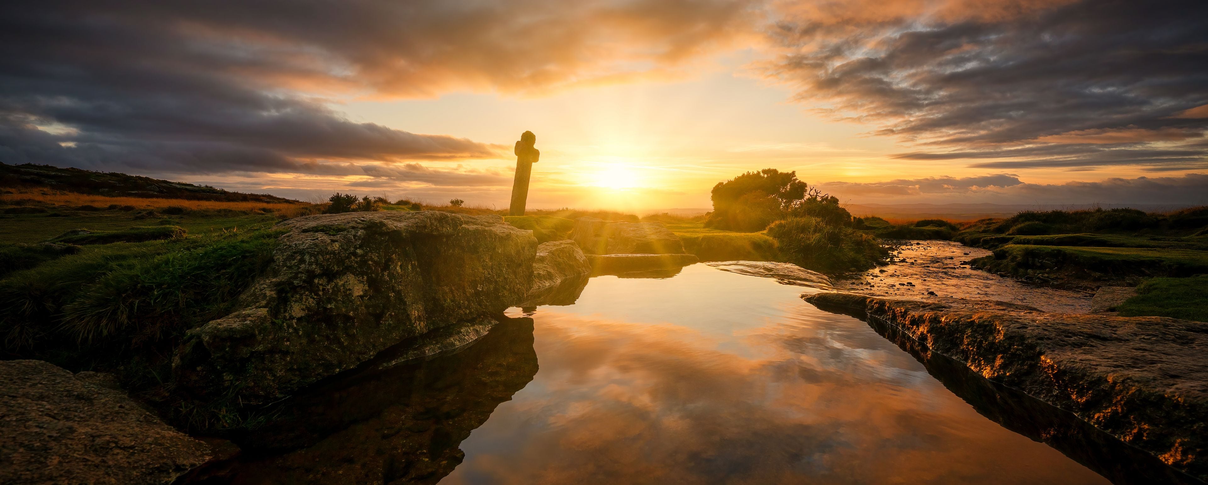 A sunset over a rocky landscape with a person standing on a rock.