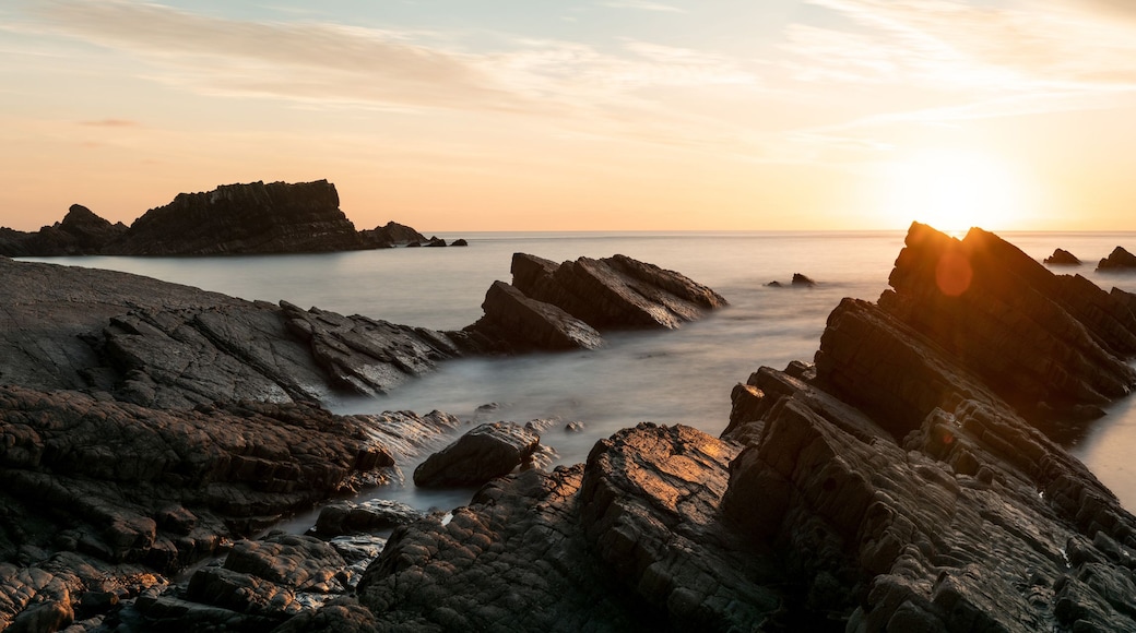 A rocky coastline with a sunset.