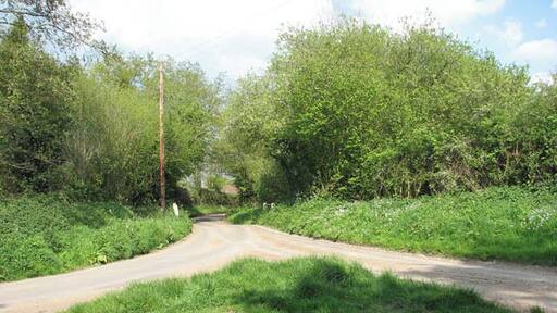 Rural crossroads. None of these country lanes has a name - the road seen straight ahead links with Hall Street further to the east. The bridge seen in mid-distance takes the road over the River Bure which here is nothing more than a small stream > 1278078. The stream here crosses the lane via a culvert which runs underneath it, only to cross underneath another lane at the same junction about 20 metres further to the west > 1278144. The River Bure rises near Melton Constable, 18 kilometres miles upstream of Aylsham, which was the original head of navigation. It flows into the North Sea by Breydon Water near Gorleston, further to the southeast.