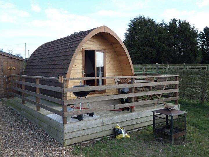 A wooden cabin with a curved roof, a porch, and a grill outside.