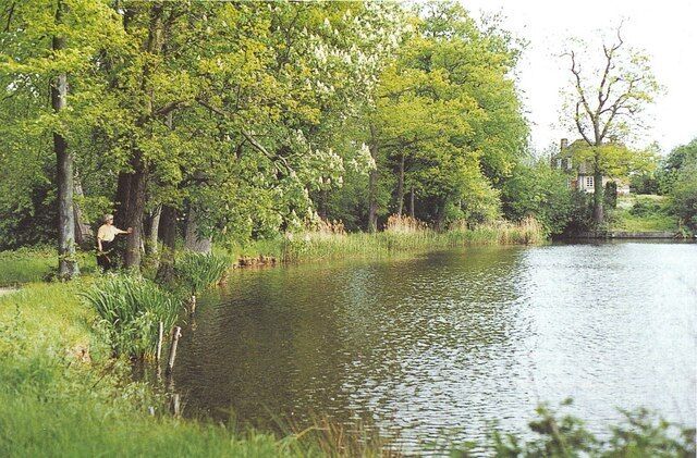 A calm river with lush greenery and a house in the background.