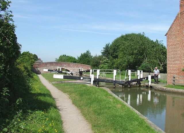 A canal with a footpath, a bridge, and a brick building.