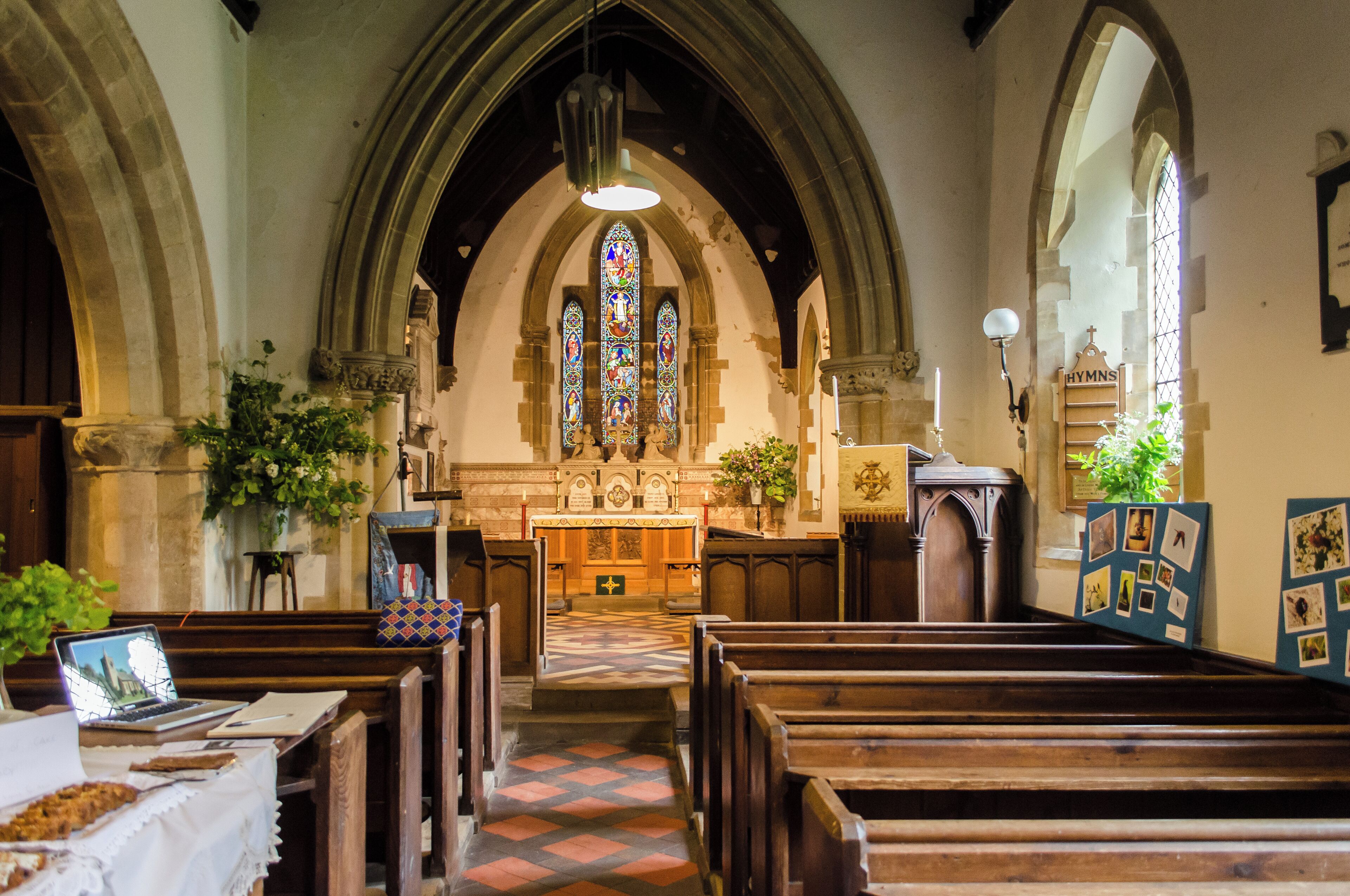 A church interior with wooden pews, stained glass windows, and a central altar.