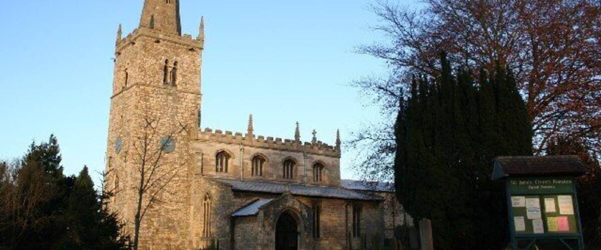 A historic church with a tall spire and a smaller building with arched windows.