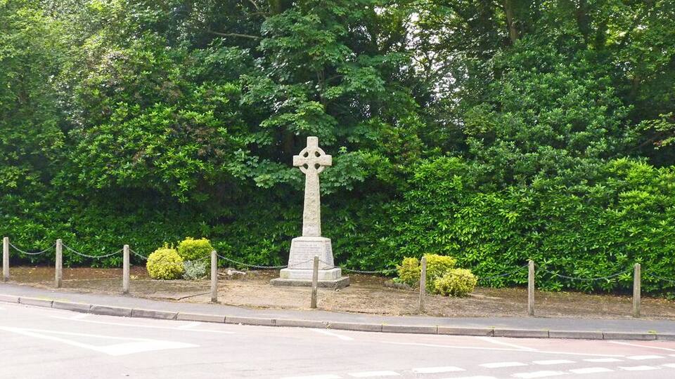A stone cross monument surrounded by greenery.