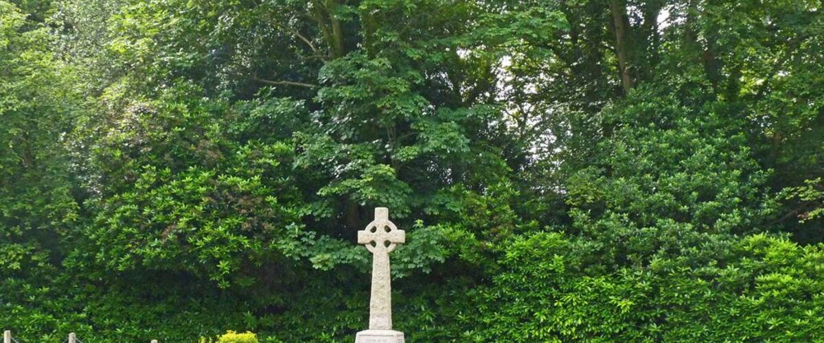 A stone cross monument surrounded by greenery.