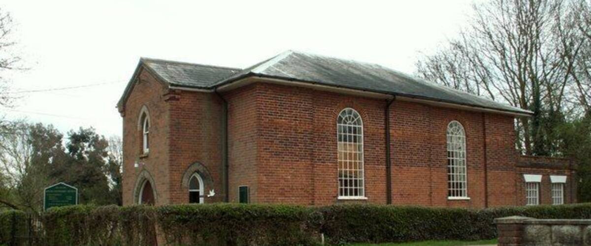 A red brick church with a large arched window and a bell tower.