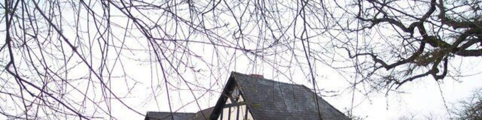 A traditional half-timbered house by a calm water body.