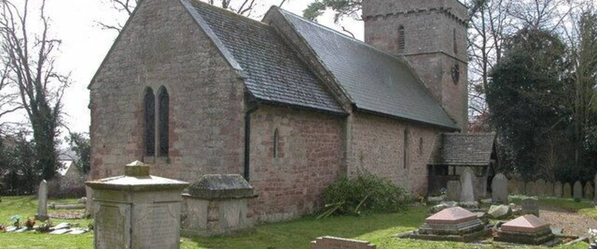 A small stone church with a bell tower and a graveyard.