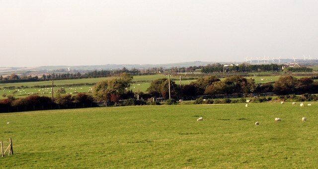 View northwards across farmland from the B5109 This image shows a considerable area of NW Anglesey. Melin Llynnon Mill at Llanddeusant can be seen background left, while in the background right, are the wind turbines north of Llyn Alaw.