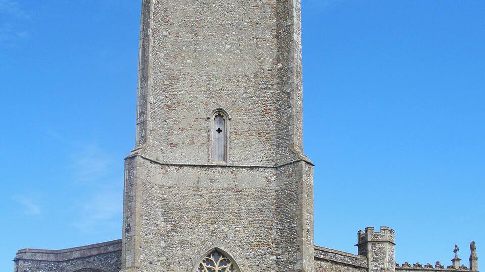 A historic stone church with a tall tower, arched windows, and a surrounding graveyard.