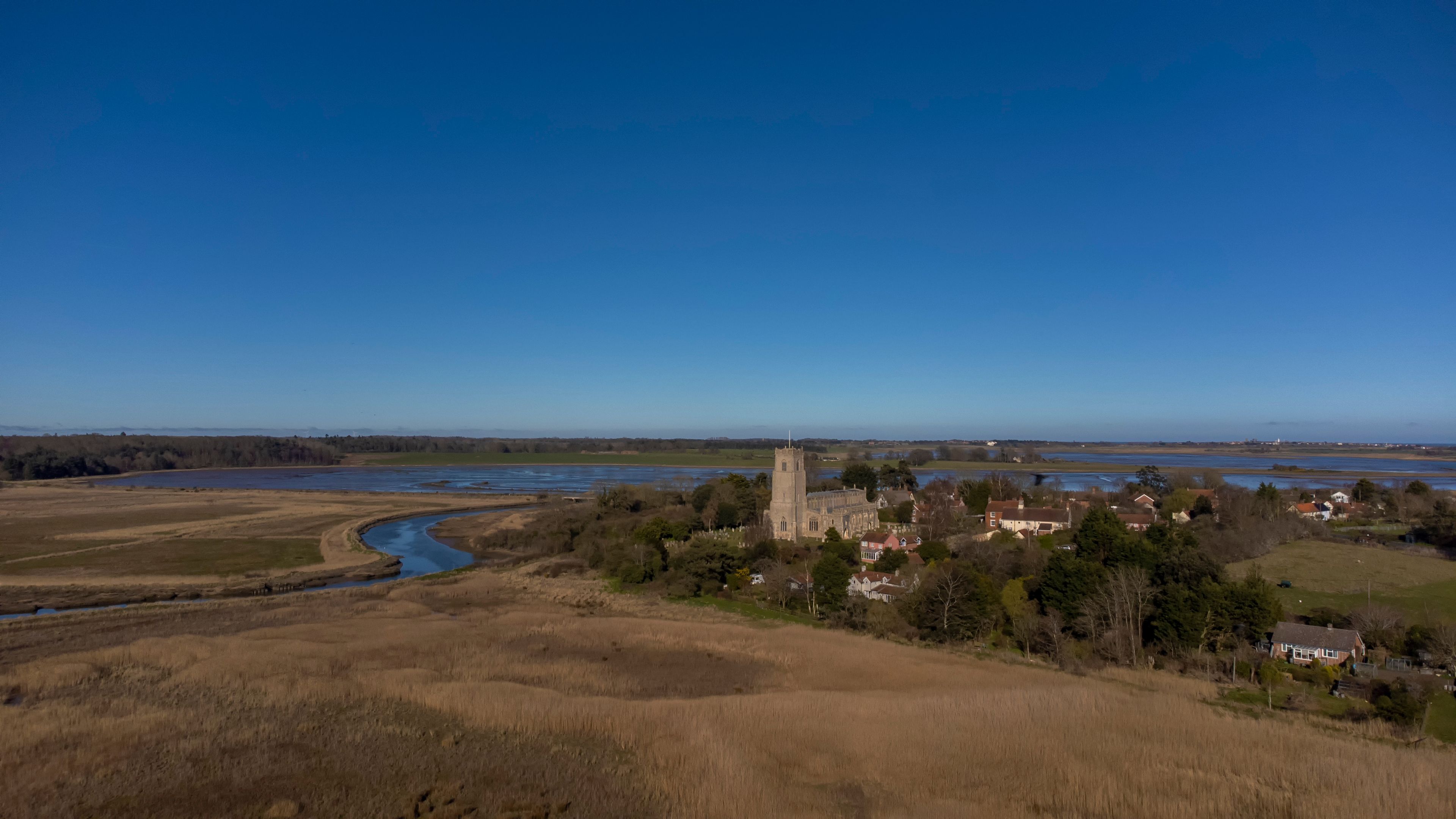 A river curving through a landscape with a church and residential buildings.
