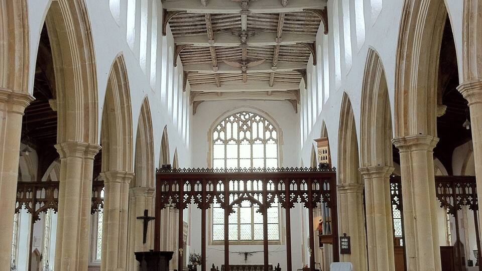 An interior of a church with high vaulted ceilings, arched windows, and wooden pews.