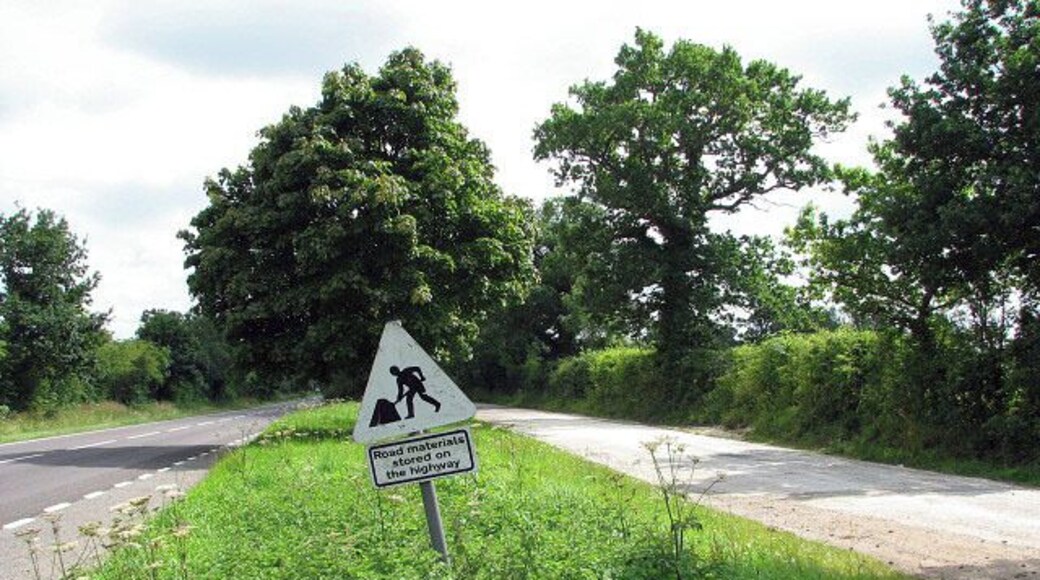 Road materials stored on the highway Announces the sign placed on the grassy strip that separates the A1067 (Norwich Road, seen at left) from an obsolete section of old road at right, by the junction with Stone Lane. The view is southerly.