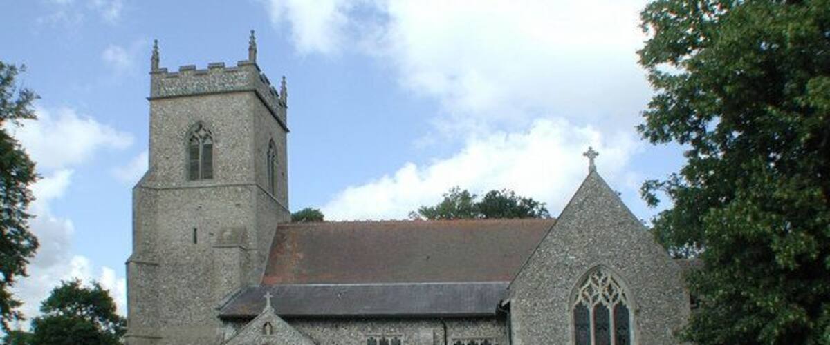A historic church with a tall tower, a pointed steeple, and a large arched window.