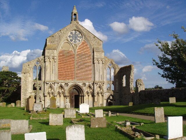 A Gothic-style church with a large rose window and a tall spire, surrounded by a cemetery with headstones.