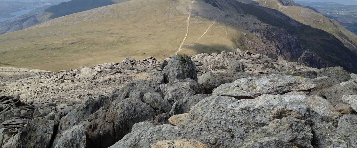 A mountain range with a clear sky and a trail leading to the summit.