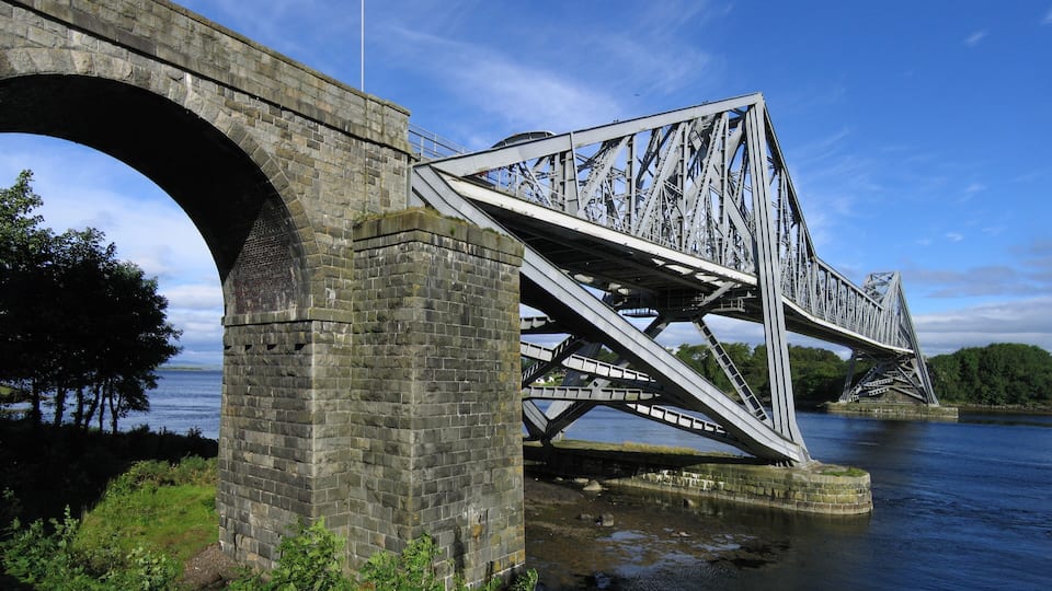 A stone bridge with a metal truss structure spanning a river.