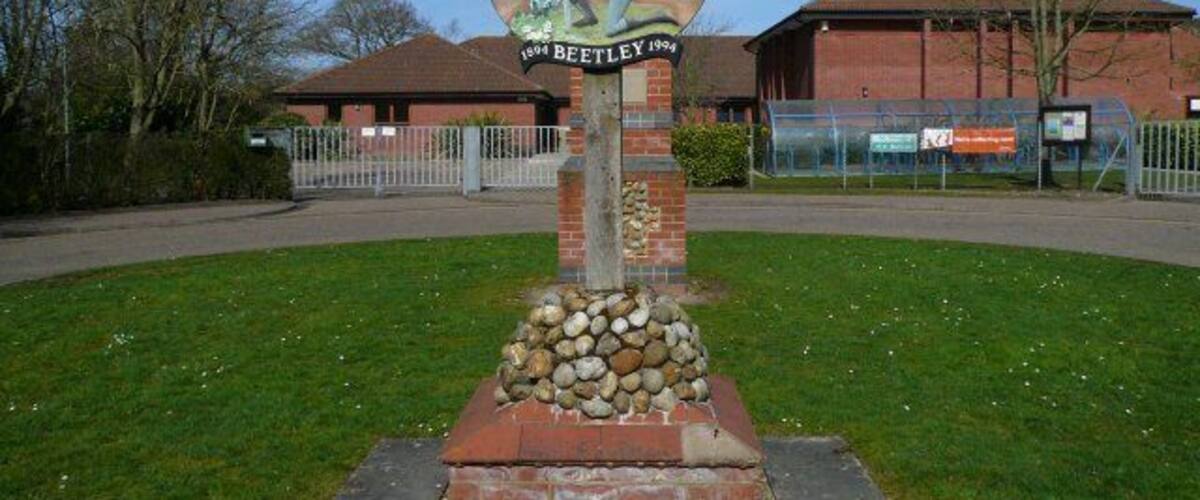 A signpost with a golfer, a brick base, and a building in the background.