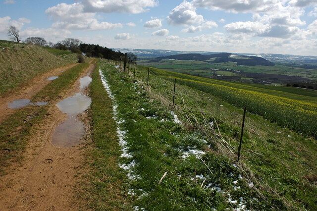 Track on Bredon Hill The track above the southern slopes of Bredon Hill is also a permissive path. To the right on the horizon are the main range of the Cotswolds Hills and in the middle distance is Dumbleton and Alderton Hill, effectively one hill but the north and south hills take their name from the respective villages at their foot.