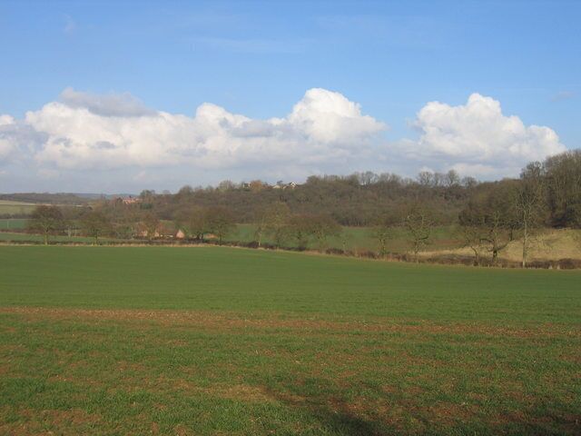 View towards Wilmcote. Looking NE across the corner of the square. The field in the foreground is in this square and is typical of the land around here as it slopes down to the stream at the bottom of the dip. Beyond the land rises steeply through the woodland with buildings on the western edge of Wilmcote visible in the distance.