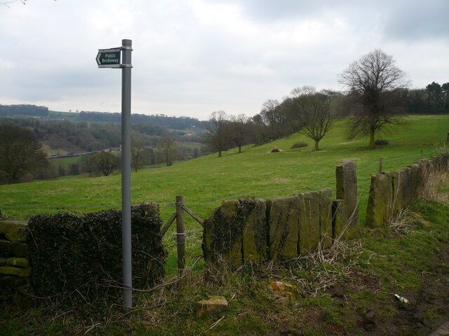 A rural landscape with a signpost indicating a public bridleway.