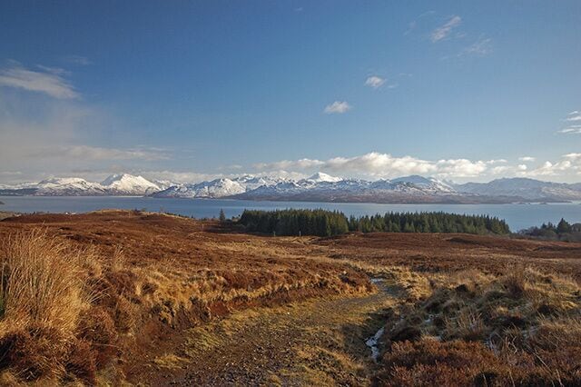 Seann Rathad na Mona The old peat road from Armadale to the moors. This view is looking back down from below Cnoc Armadail towards the forest behind Armadale Castle. The water in the background is the Sound of Sleat, with snow capped mountains of Knoydart beyond.