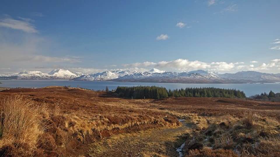 Seann Rathad na Mona The old peat road from Armadale to the moors. This view is looking back down from below Cnoc Armadail towards the forest behind Armadale Castle. The water in the background is the Sound of Sleat, with snow capped mountains of Knoydart beyond.
